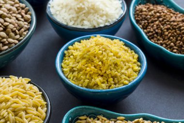 Siyah yüzey üzerinde seramik kâselerde pişmemiş kuru gevrek grubu. Seçilmiş bulgur kasesi.