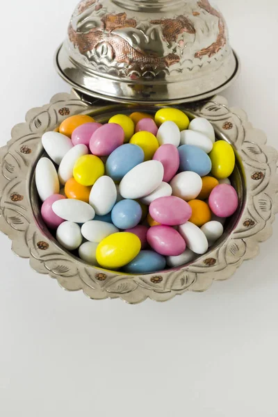 白色表面带有复制空间的老式铜碗中五彩缤纷的杏仁糖果 庆祝活动的概念形象 — 图库照片