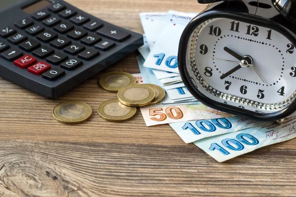 带有计算器和老式闹钟的木制表面土耳其里拉钞票 — 图库照片
