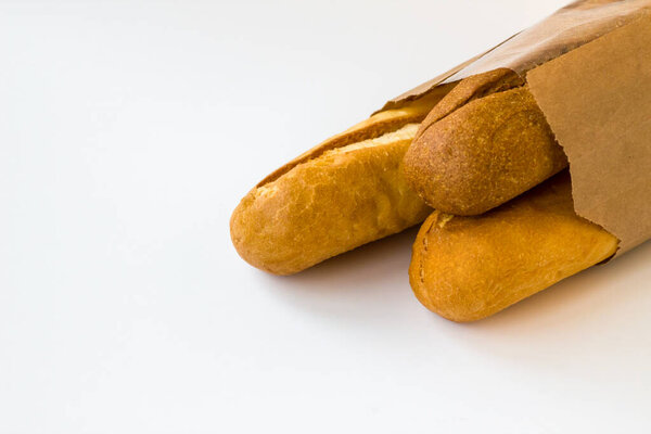 Whole wheat baguette breads in kraft paper bag on a white background with copy space