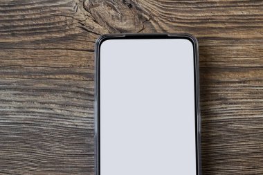 Ahşap yüzey üzerinde beyaz boş ekranlı akıllı telefon, yarım görünüm