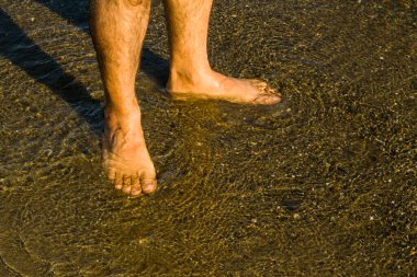Unknown man bare feet standing on the beach near sea,summer time