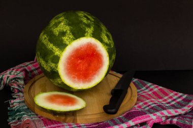 Çizgili üst kesim karpuz, yeşil kabuklu, tahta tepside bıçaklı.