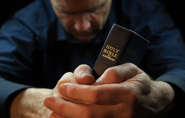 Člověk se modlí, drží svaté Bibli. — Stock fotografie