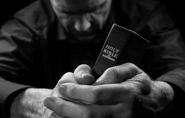 Ein betender Mann hält eine heilige Bibel in der Hand. — Stockfoto