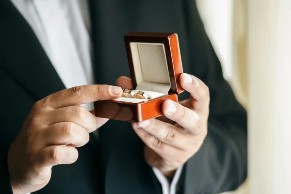 Bräutigam in Anzug und Krawatte hält Eheringe — Stockfoto