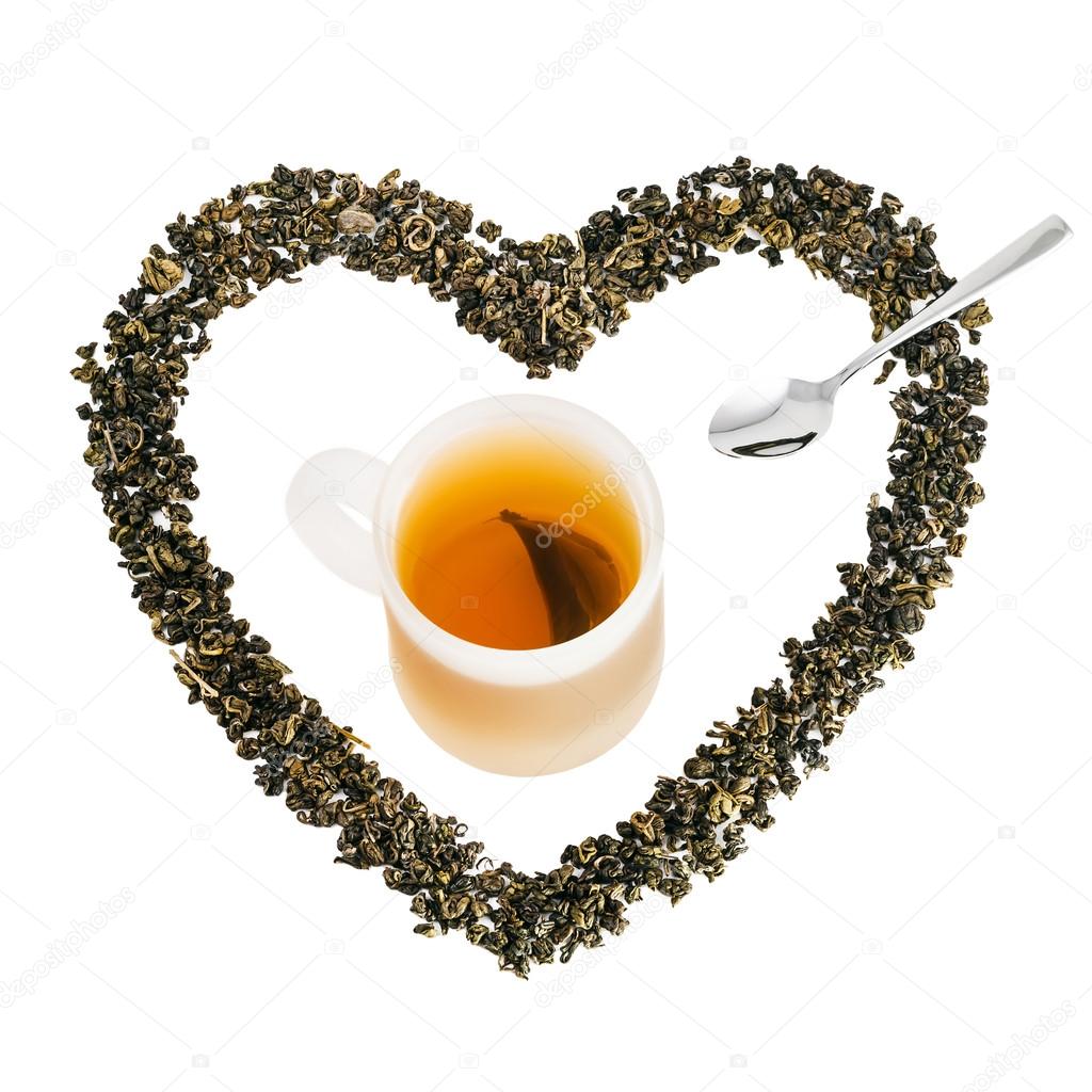 Green tea leaves in heart shape with cup of tea and silver spoon