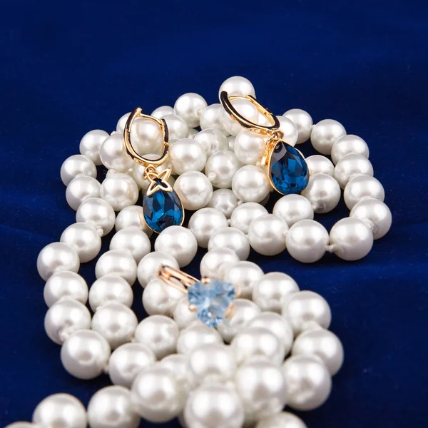 金耳环，在蓝色背景上的珍珠项链 — 图库照片