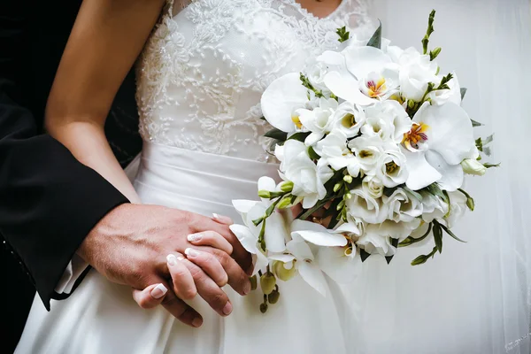 Bride with wedding bouquet of white orchids and groom holding ea — Stock Photo, Image