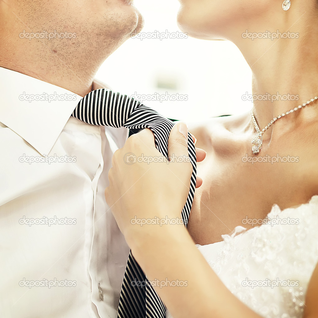  Bride and groom. Woman pulling on mans tie.