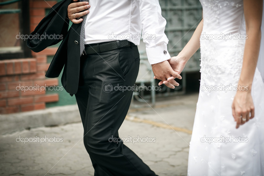 Groom and bride walk and hold each others hands