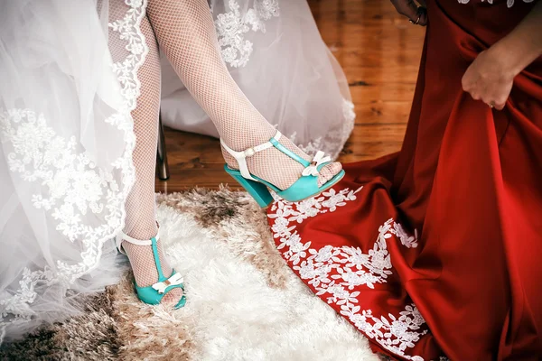 Brautjungfer hilft Braut, Cyan-Hochzeitsschuhe anzuziehen. — Stockfoto
