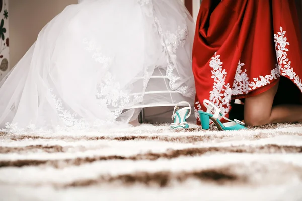 Bridesmaid helps to bride to put on cyan wedding shoes. — Stock Photo, Image