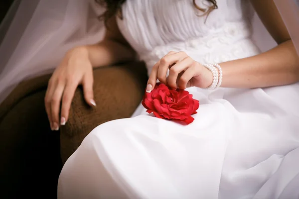 Mariée assise élégamment, touche doucement la rose — Photo