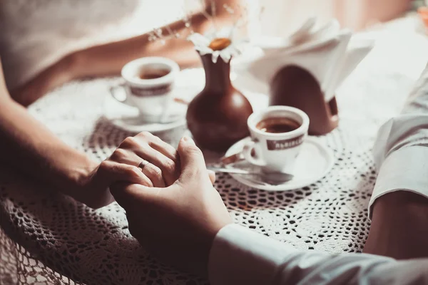 Verliebtes Paar trinkt Kaffee im Café und hält sich die Hand. lizenzfreie Stockbilder