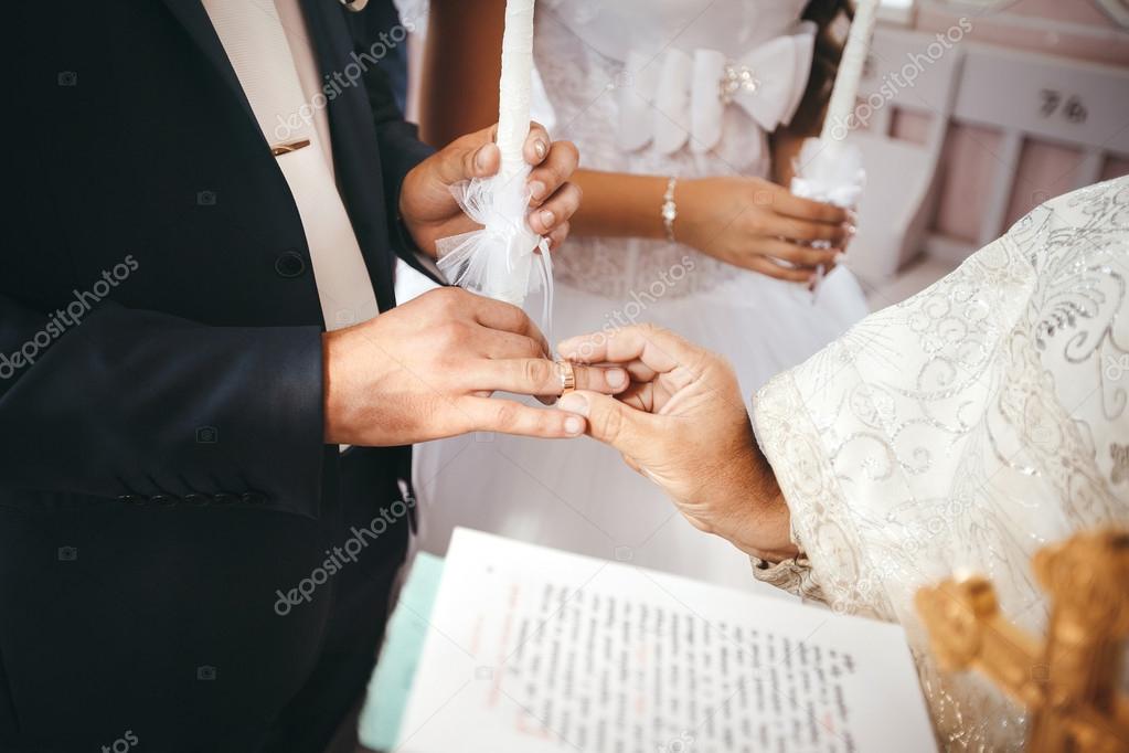 Wedding ceremony in church. Priest puts a wedding ring on groom's finger