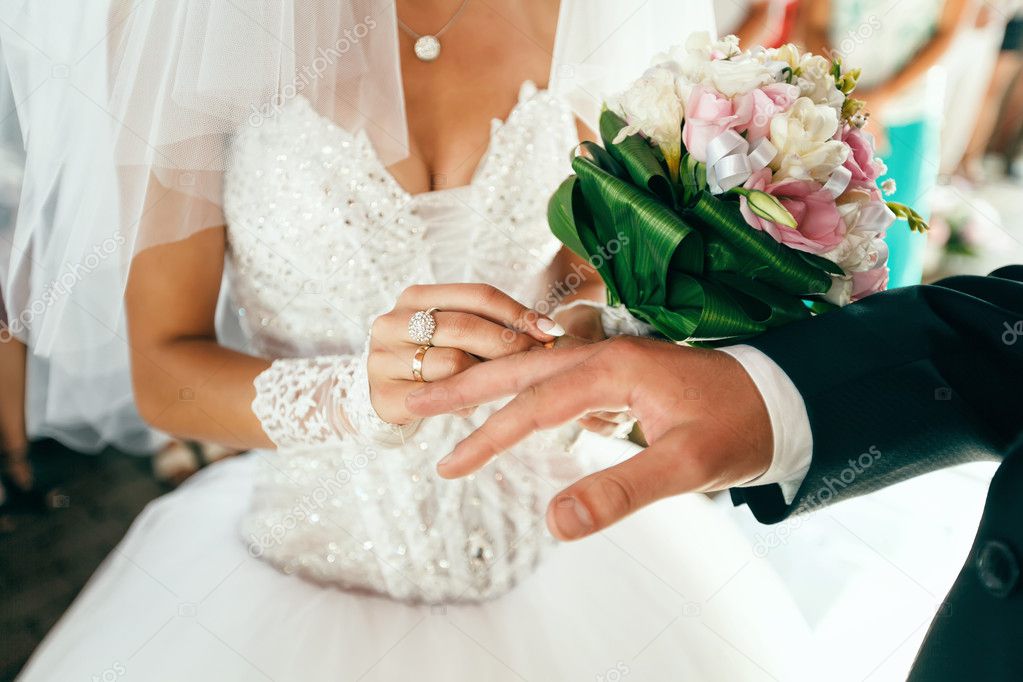 Bride puts on wedding ring on groom's finger 