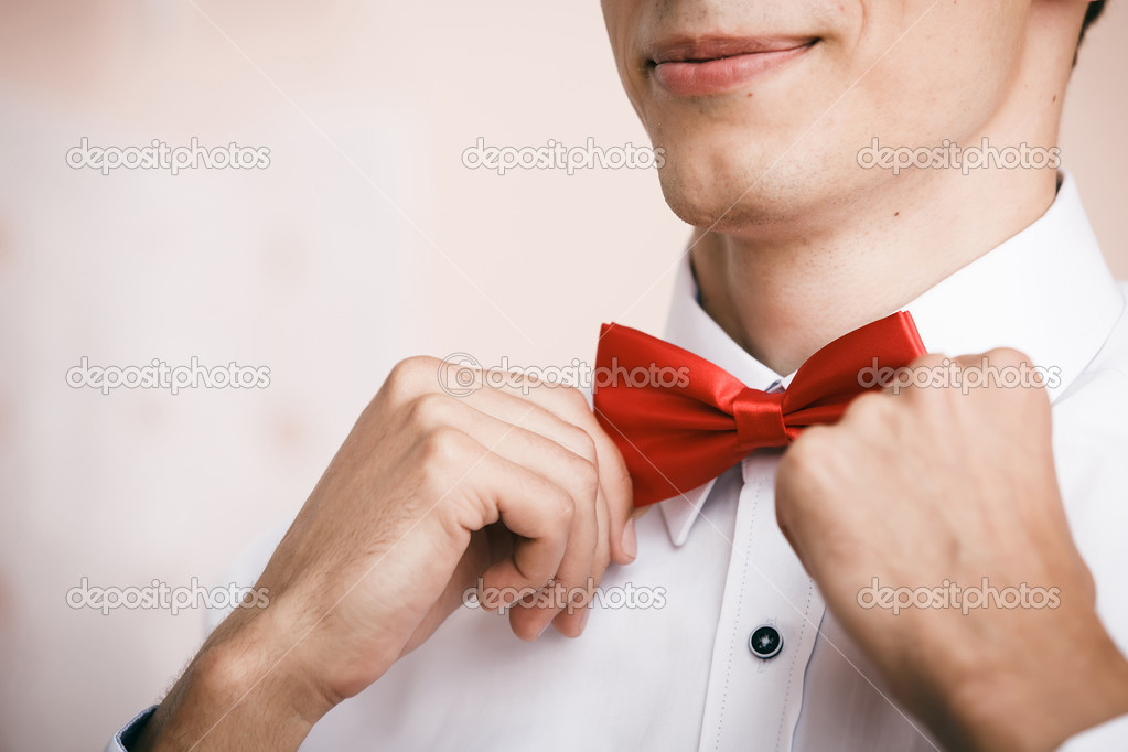Man puts on red bow tie. Close up. Shallow depth of field.