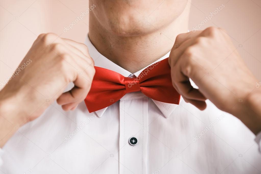 Man puts on red bow tie. Close up. Shallow depth of field.