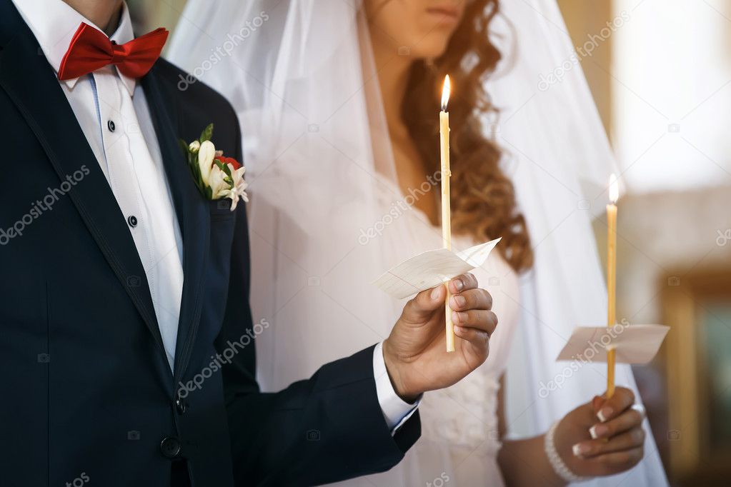 Wedding ceremony in church. Groom and bride hold candles.