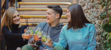 Mutlu arkadaşlar merdivenlerde oturup uzun zamandır beklenen buluşmalarını meşrubatlarla, portre fotoğraflarıyla kutluyorlar.