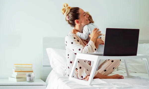 Mother hugs her daughter while she is working frome home - Smart working concept