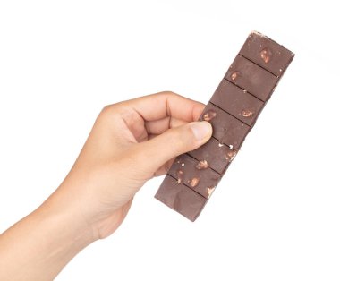 El ele tutuşmuş, fındık bademli çikolata beyaz arka planda izole edilmiş parçalara ayrılmış.