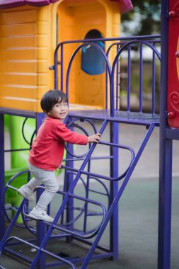 Çocuk kaydırağın üzerinde merdivenleri tırmanır..