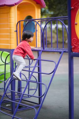 Çocuk kaydırağın üzerinde merdivenleri tırmanır..