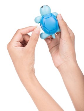 El ele tutuşan Oyuncak Kaplumbağa Beyaz bir arka planda yalıtılmış.