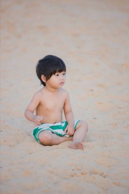 Kumsalda kumsalda küçük bir çocuk.