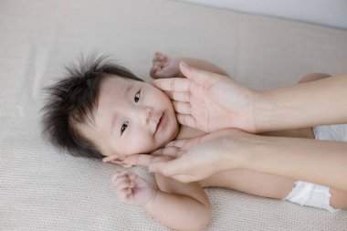 Anne yatakta masaj yapan bir bebek.