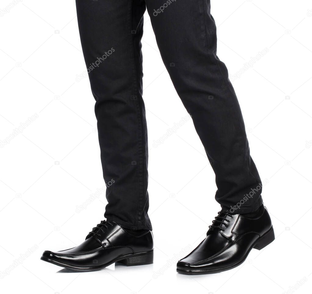 Man's feet in black trousers and black shoes isolated on white background