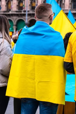 Genç adam, Rusya 'nın işgalini protesto etmek için Ukrayna bayrağına sarılmış.