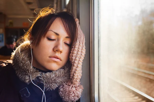 Спящая девушка в наушниках в поезде — стоковое фото
