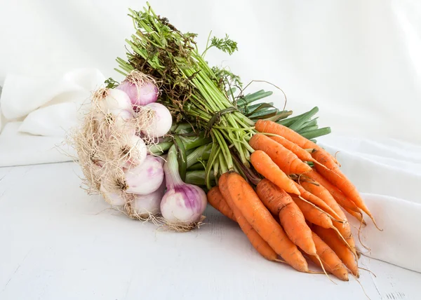 หัวหอมและแครอทบนพื้นหลังไม้และผ้าขาว — ภาพถ่ายสต็อก