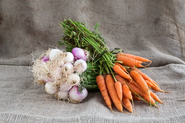 Sipulit ja porkkanat puinen tausta ja säkki — kuvapankkivalokuva