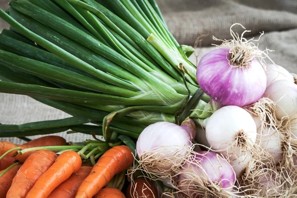 Zanahorias y cebollas sobre fondo de mesa y saco tejido —  Fotos de Stock