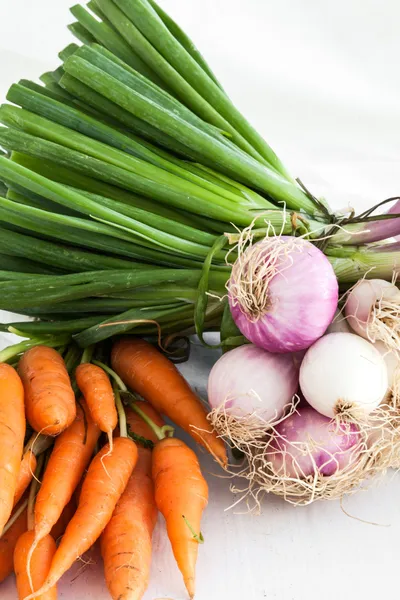 Zwiebeln und Karotten auf weißem Tischhintergrund und Gewebe — Stockfoto
