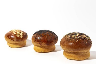 Yüksek kontrastlı ışıkla beyaz arka planda tohumlu ev yapımı brioche çörekleri. İzole edilmiş