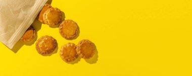 Renkli karton üzerinde taze ev yapımı kurabiyelerin arkaplanı ve yukarıdan gelen güneş ışığı. Düz yatıyordu