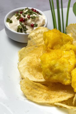 Ev yapımı balık, tartar soslu patates kızartması ve mermer kaplama limonlu kağıt külah.