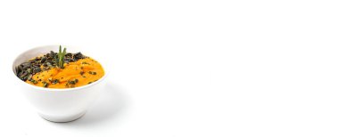 Homemade pumpkin cream soup bowl background decorated with pumpkin seeds, black sesame, aromatic herbs, fried bread. healthy food concept