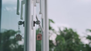 Bir evin kilidini açmak için ev sahibinin anahtarı kapıya takılı. Kira ve satış için ikinci el ev. Anahtarlık rüzgarda savruluyor. Yeni ev sahibi, kira, satış, yenileme, yatırım.