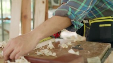 Küçük bir kereste işi olan Asyalı adam mobilya üretimi için odun hazırlıyor. Marangoz bir mezura ile ahşabı ölçer ve bir sonraki adım için bir çizgi çeker. ev eşyaları kavramı.