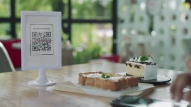 Kadın, kafeteryada nakit olmadan dijital ödeme yapmak için akıllı telefon kullanarak QR kodunu tarıyor. Menüyü ve siparişi seçin ve indirimi toplayın. Cüzdan, teknoloji, online ödeme, kredi kartı, banka uygulaması, tarama