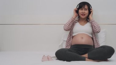 Hamilelik boyunca dinlenmek için müzik dinleyen Asyalı bir kadın. Hamileyken müzik dinlemek çocuğunuzun beyninin gelişimine yardımcı olur. Hamilelikten bu yana çocuk gelişimi kavramı.