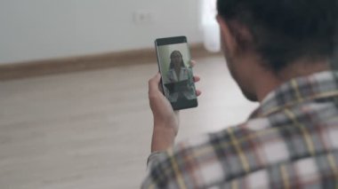 Ruh sağlığı sorunları olan bir adam cep telefonuyla bir doktora danışıyor. Çevrimiçi tıbbi hizmetler sosyal mesafelerin risklerini azaltır. Online tedavi kavramı