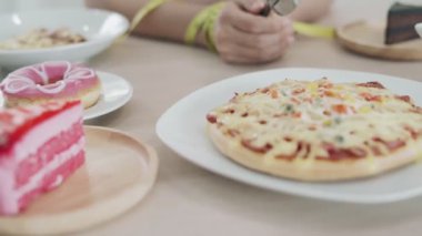 Diyet Kadınları ellerinin etrafına bant sardı. Kadınlar kendilerini şişmanlatan ve kilolarını kontrol etmelerini zorlaştıran yağlı gıdalardan ve abur cuburlardan kaçınıyorlar. Diyet ve kilo kaybı kavramı.