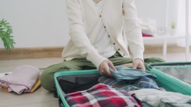 Bir kadın elbiselerini katlar ve bir yolculuğa hazırlanmak için çantasına koyar. Bir kadın iş gezisi için çantalarını hazırlar. Seyahate hazırlanma konsepti.